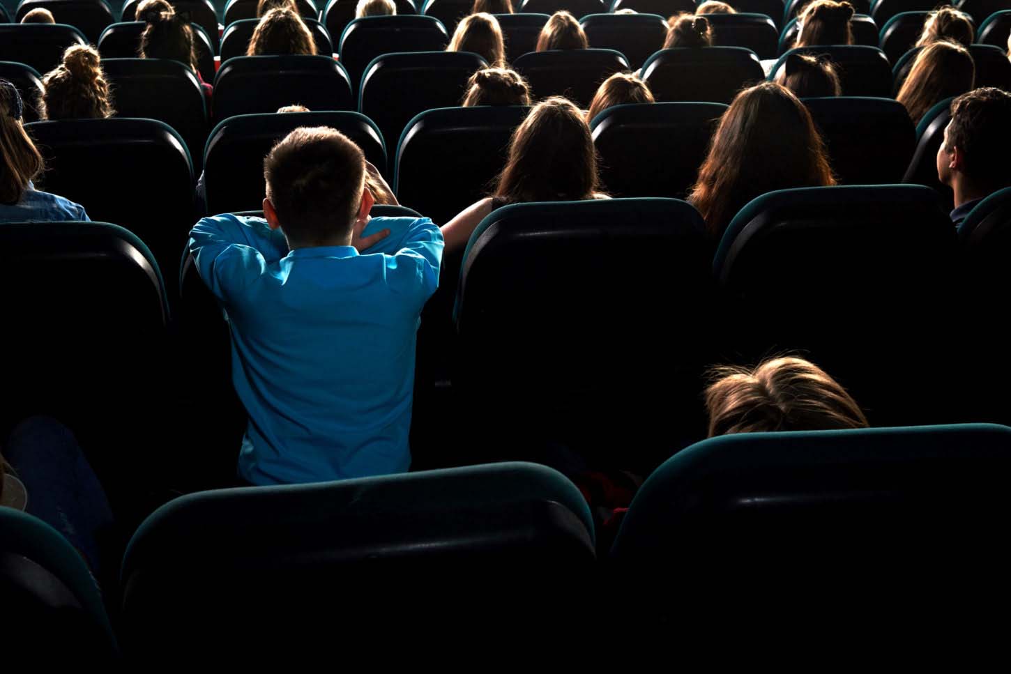 Rearview shot of little kids watching movies at the cinema sitting in the dark auditorium leisure hobby entertainment kids childhood modern multiplex activity lifestyle holidays concept.